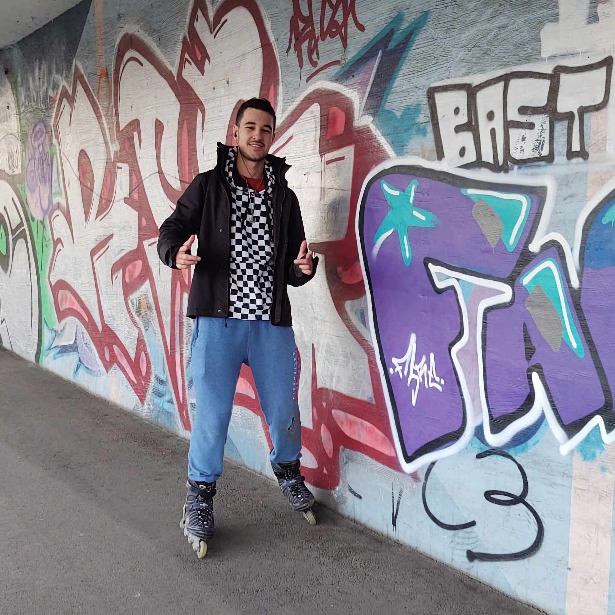 Lucas Goldner with inline skates posing in front of a graffiti wall